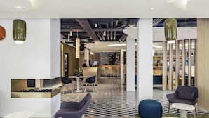 Een moderne lobby met een receptiebalie, een zithoek en een bar.