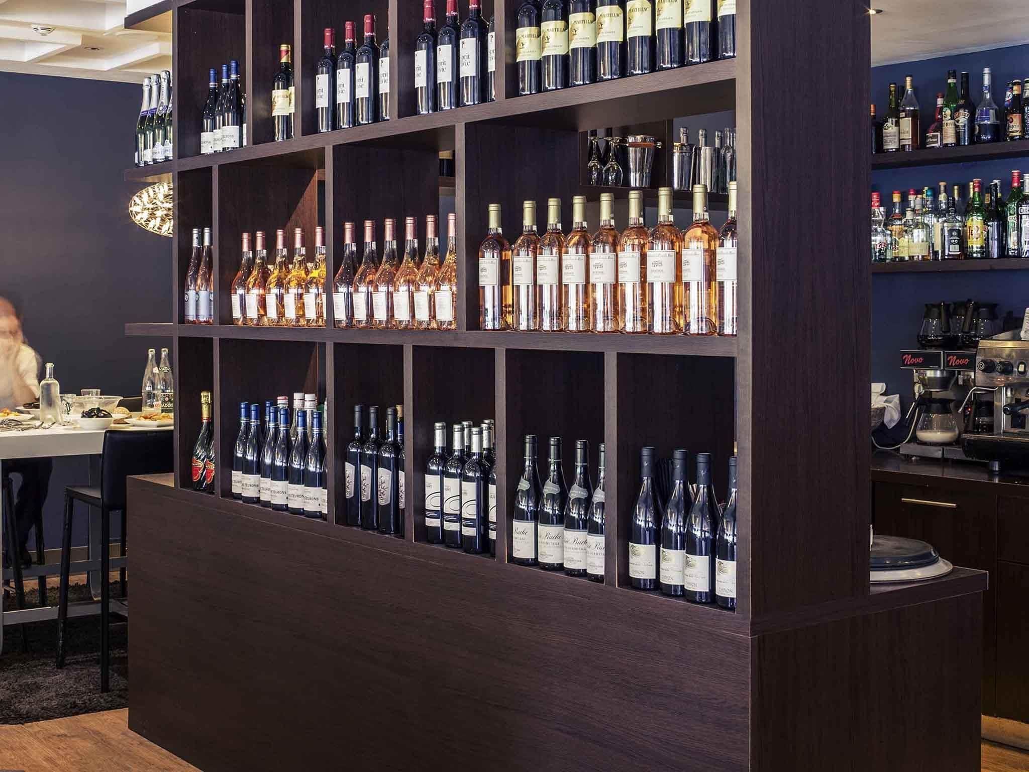 Zona de bar con estantes de botellas de licores varios, una máquina de café y una mesa de comedor con sillas.