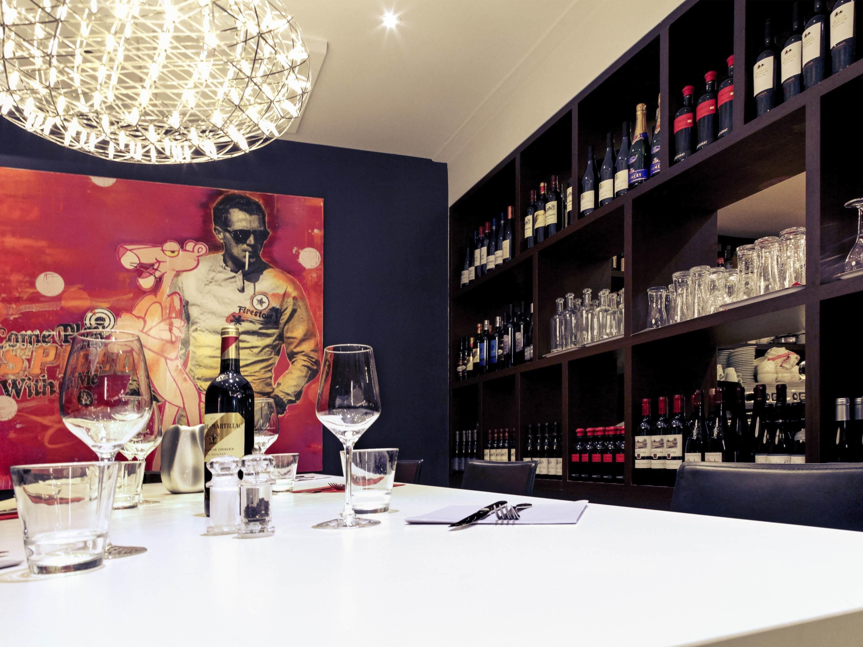 Uma área de bar com uma garrafa de vinho, copos e uma luminária decorativa.