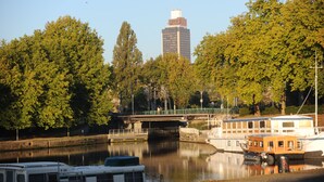 A river with boats, a bridge, and a tall building in the background. - Mercure Nantes Centre Gare (Nantes)