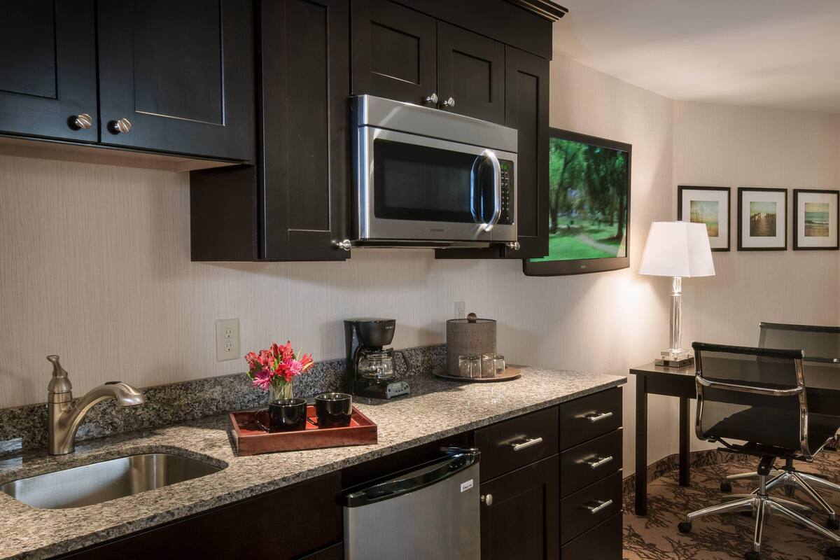 A modern kitchen with a stainless steel microwave, granite countertop, and a coffee maker.