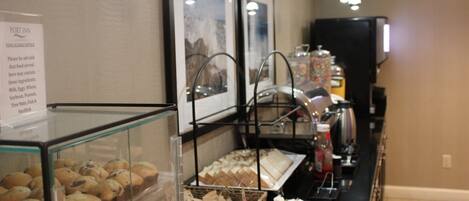 A buffet area with various food items displayed in glass cases and baskets, including pastries and sandwiches.