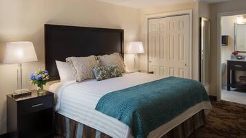 A hotel room with a large bed, two bedside tables, a nightstand, a mirror, and a door.