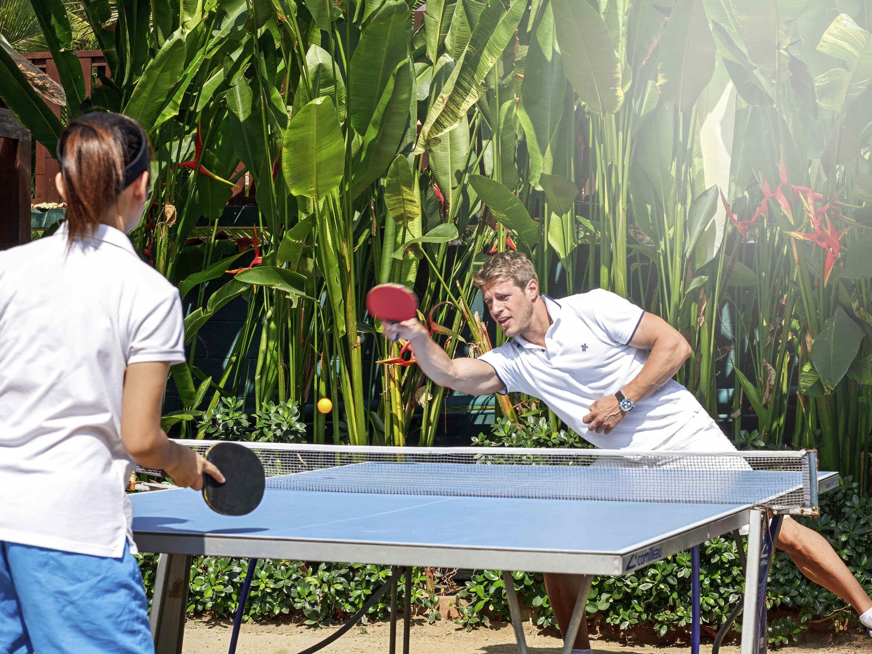 Une table de ping-pong avec un filet, entourée d’une végétation luxuriante.