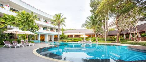 Un hotel con piscina, sillones de descanso y palmeras.
