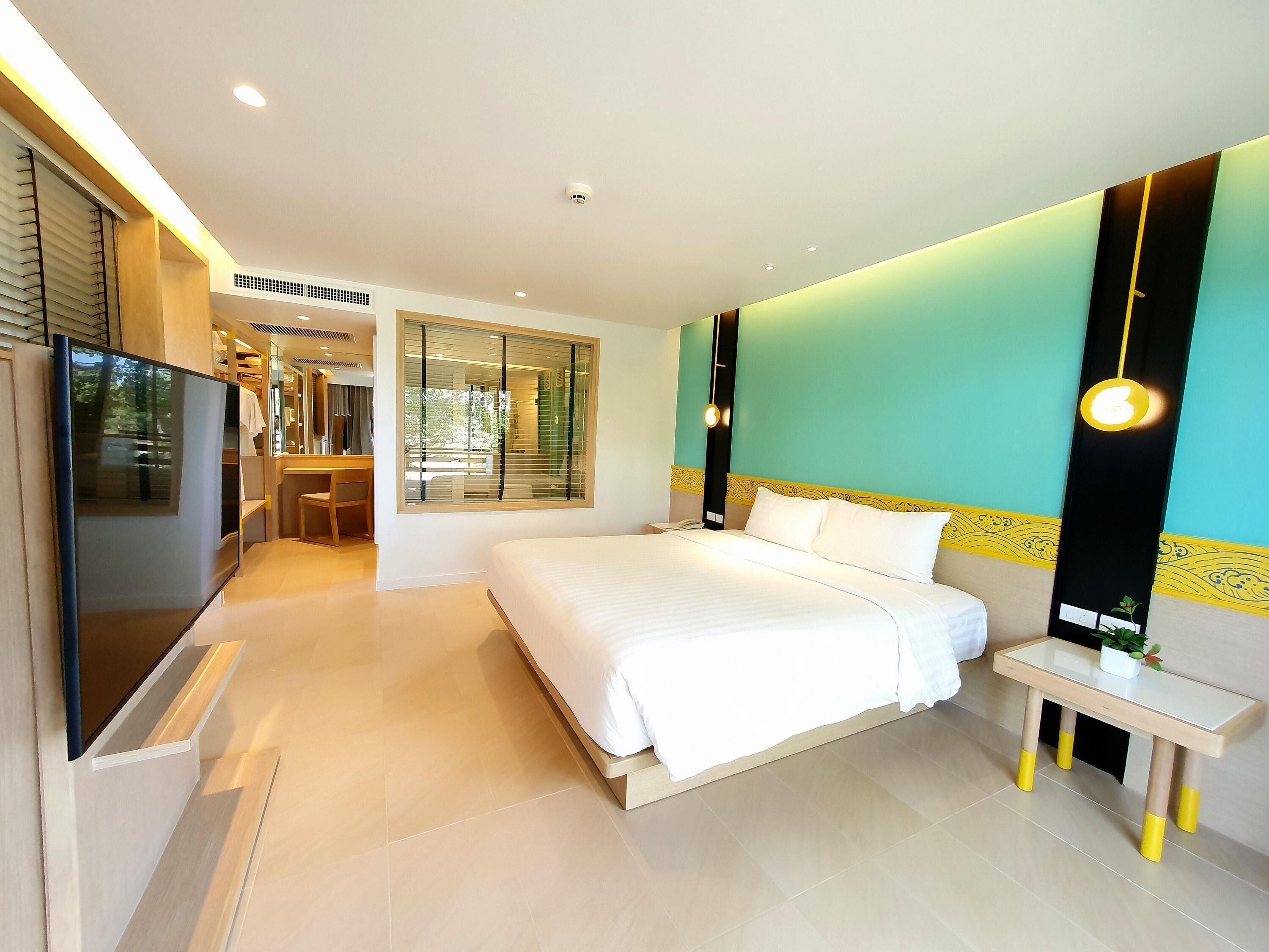 A modern hotel room with a large bed, a desk, and a television.