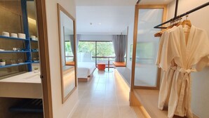 A hotel room with a large mirror, a robe hanging on a rack, and a view of the outdoors through a large window.