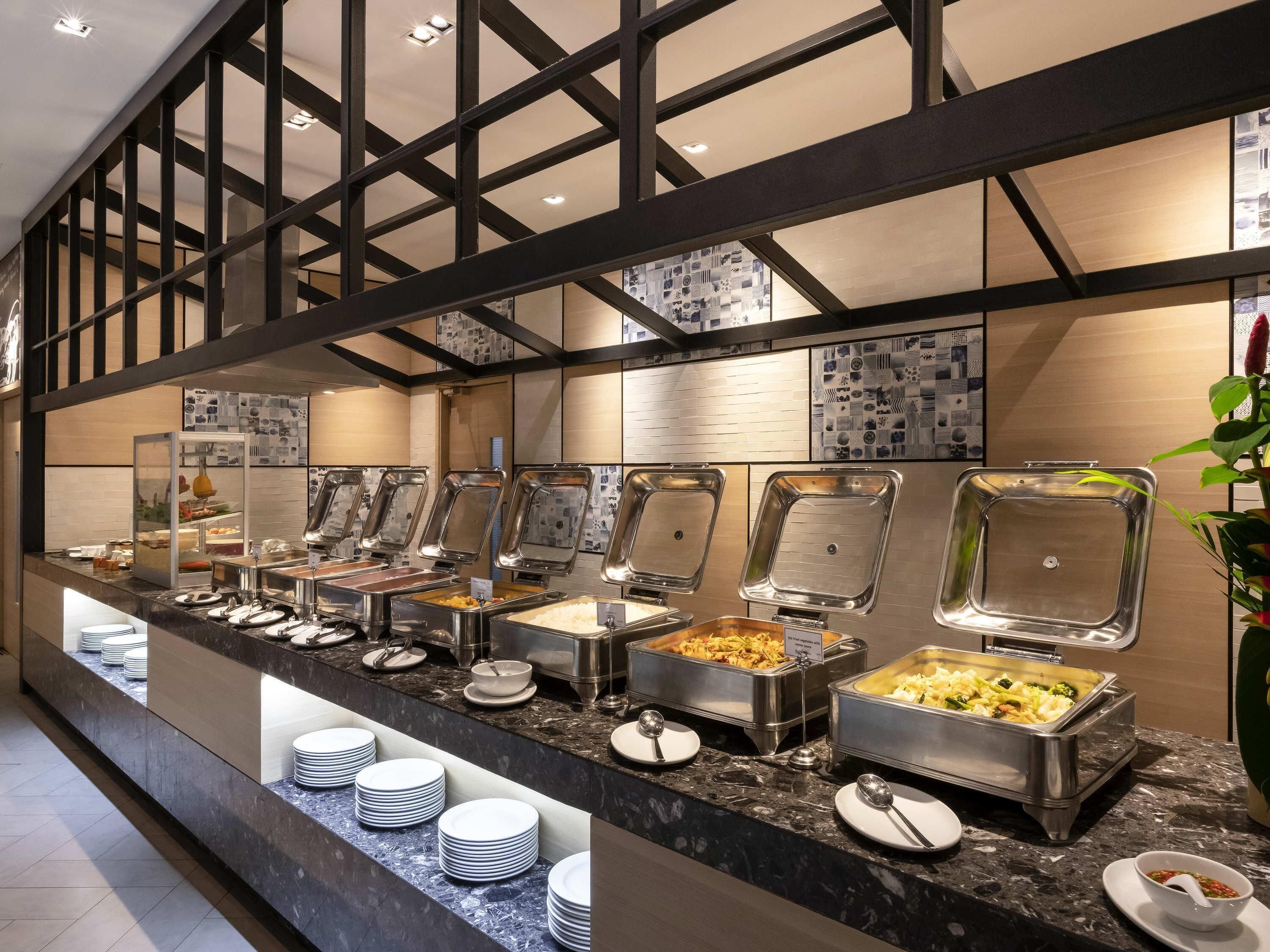 A buffet setup with multiple food service stations, a marble countertop, and a decorative wall with a geometric pattern.