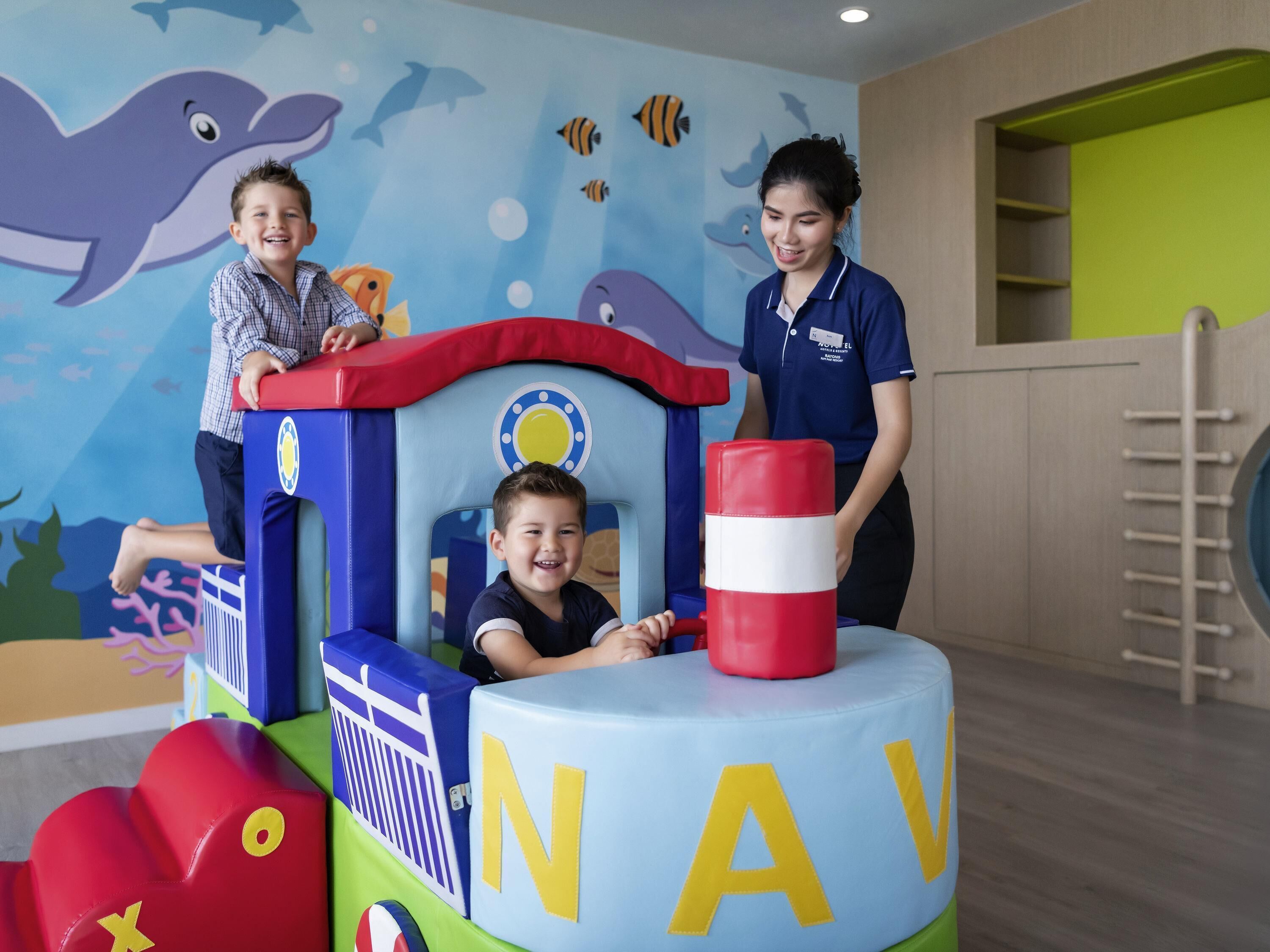 A play area with a play structure labeled 'NAV' and a child inside.