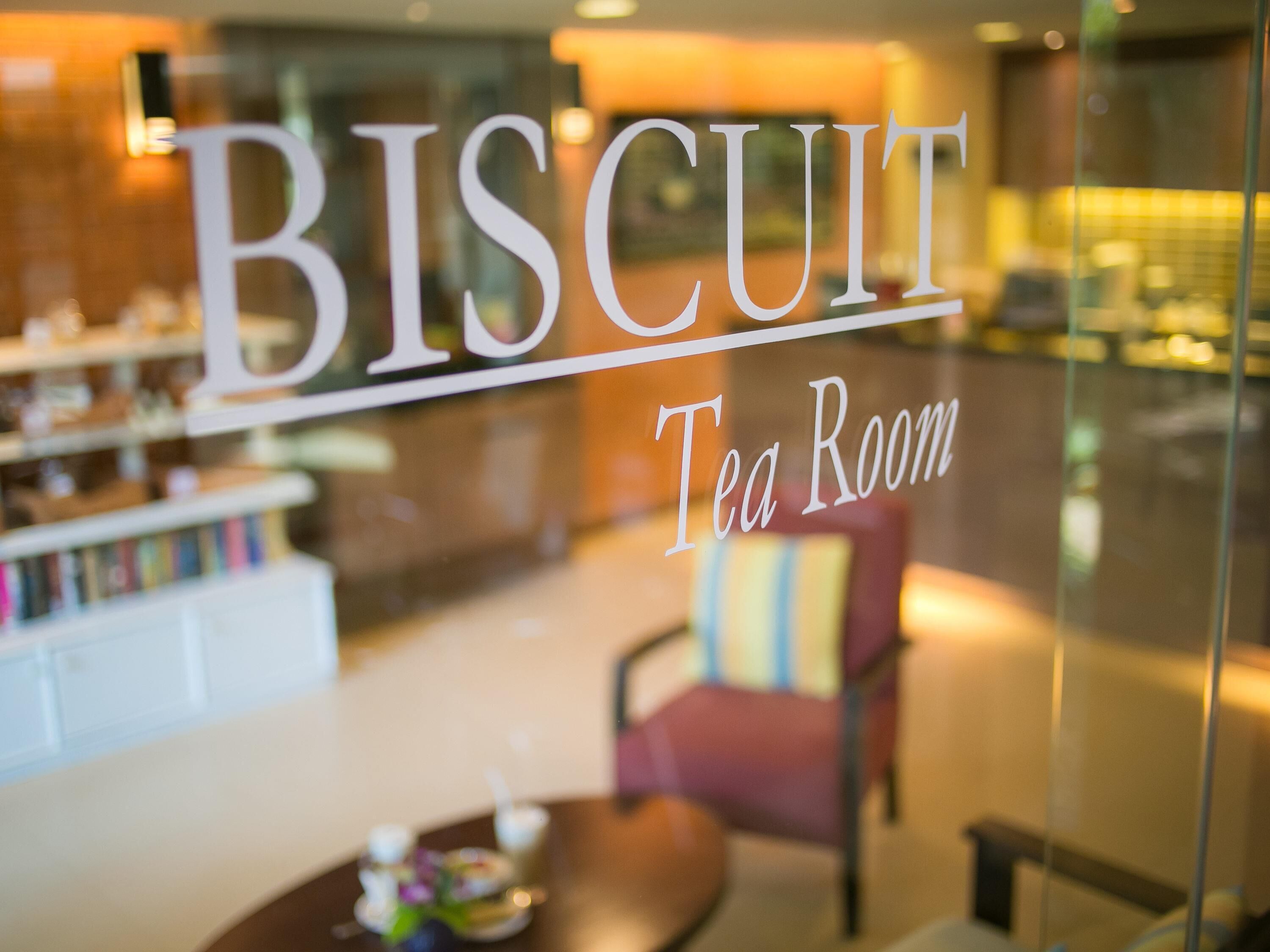 Un letrero indica una sala de té llamada 'BISCUIT', con un interior moderno visible a través de la ventana.