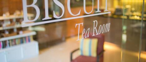 Un letrero indica una sala de té llamada 'BISCUIT', con un interior moderno visible a través de la ventana.