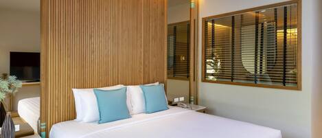 A modern hotel room with a large bed, wooden panel wall, and a large window with blinds.