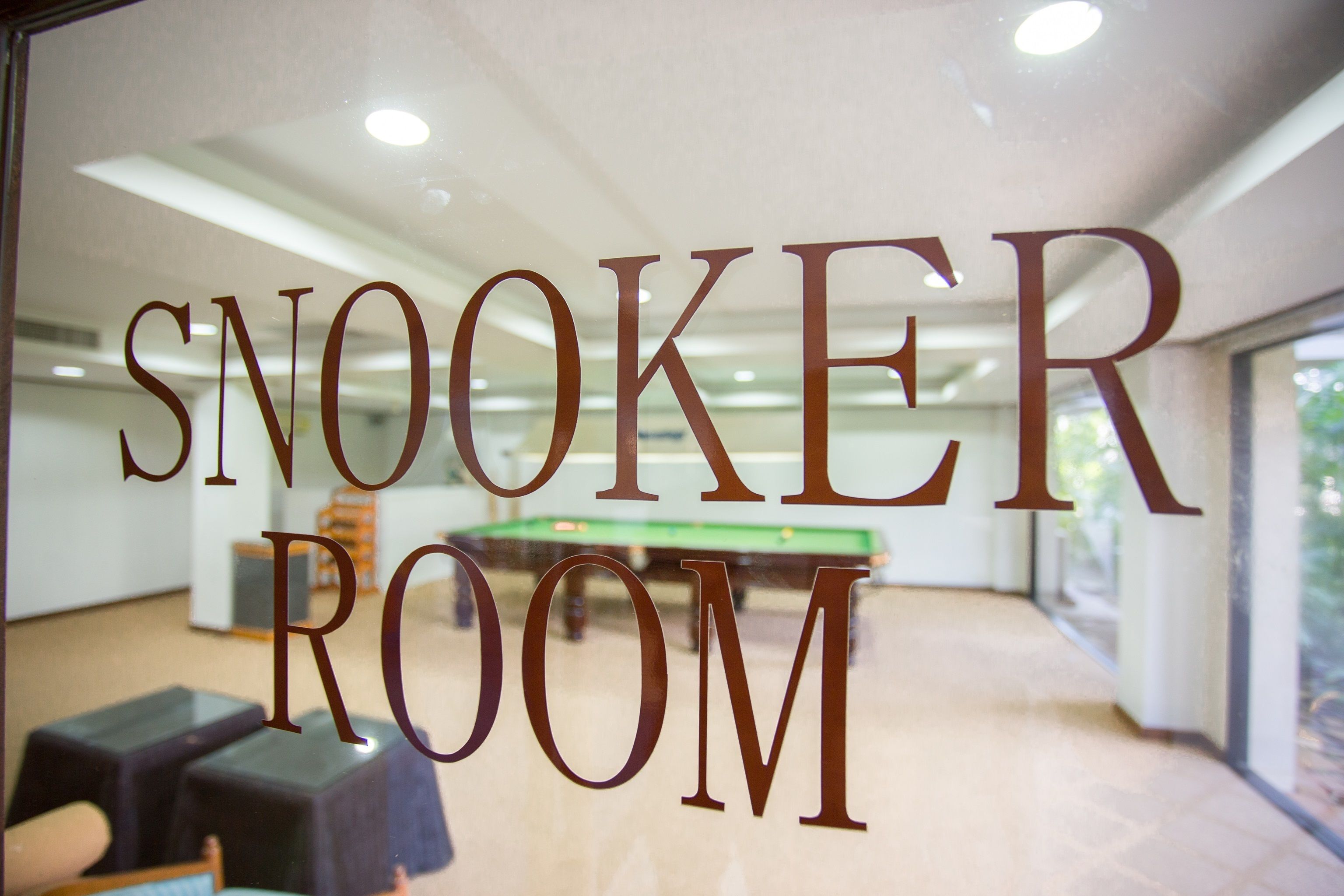 A room with a pool table and the words "SNOOKER ROOM" on the glass door.