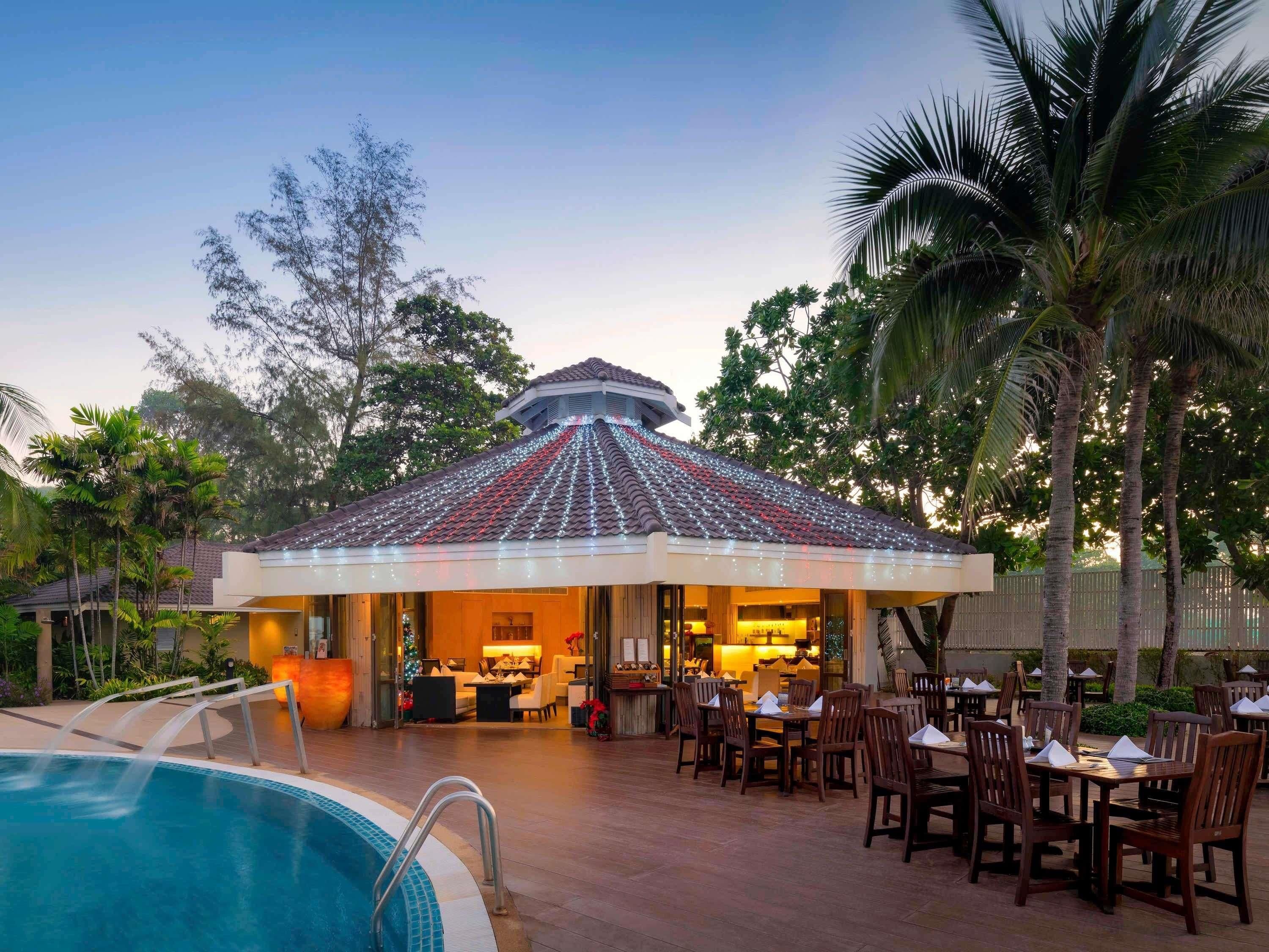 A poolside area with a covered seating area and a dining setup.