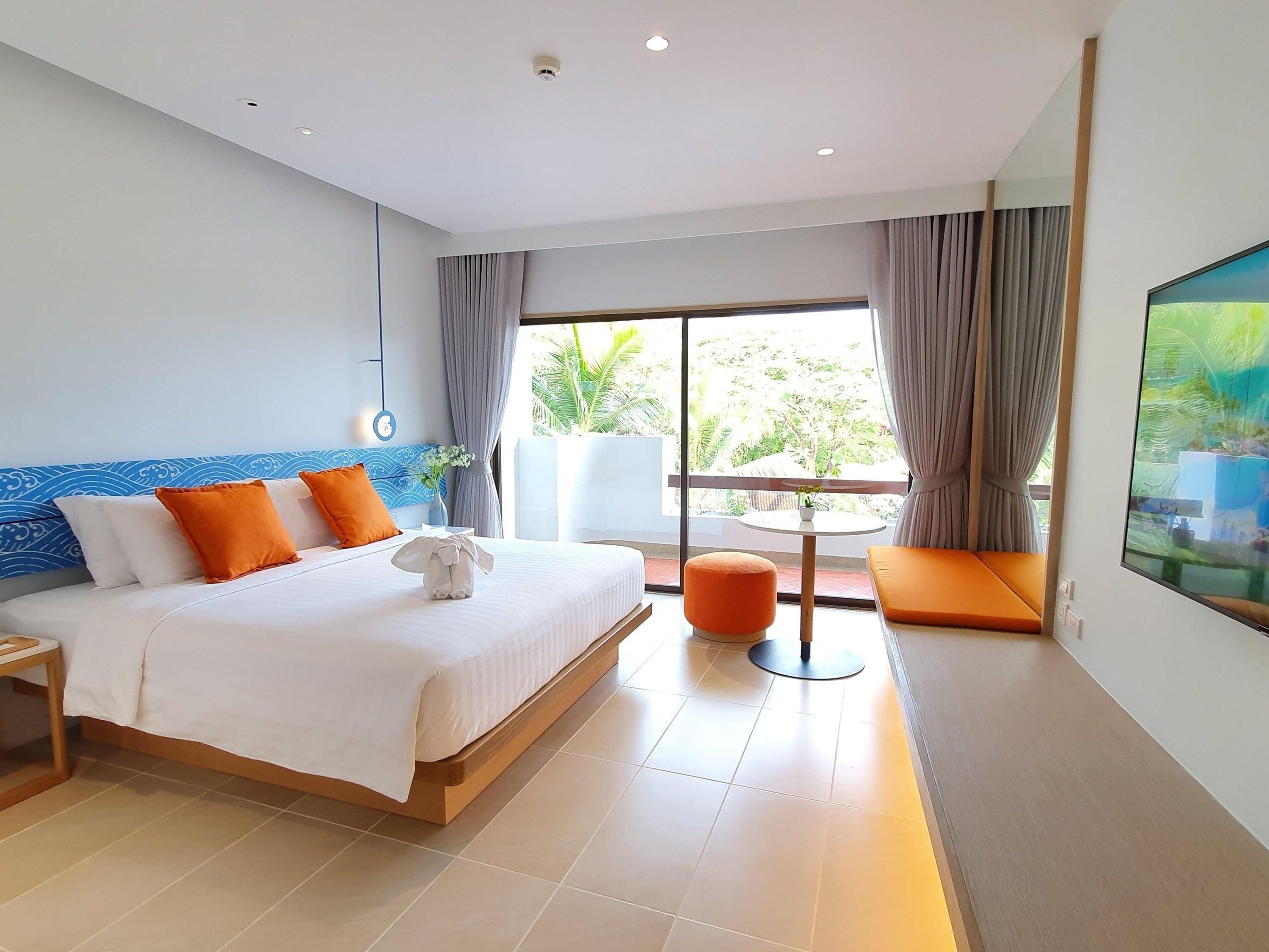 Una habitación de hotel con una cama grande, una mesita, una silla y un televisor.