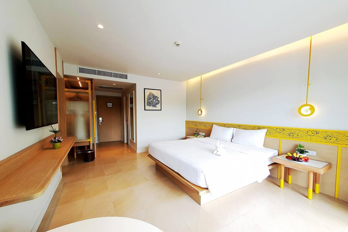 Una habitación de hotel moderna con una cama, una mesita de noche y un televisor montado en la pared.