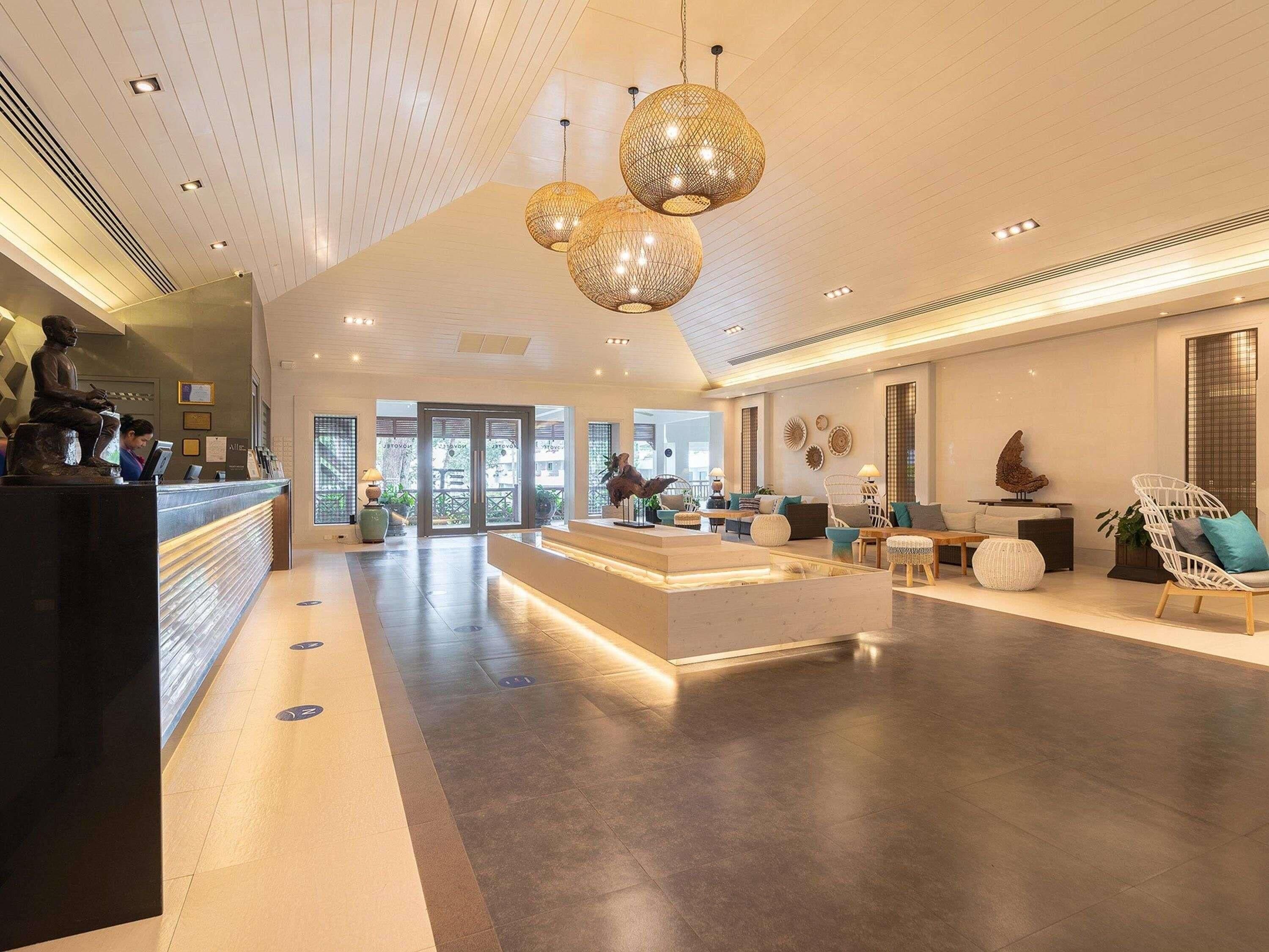 Um hall amplo com balcão de recepção, área de estar e iluminação decorativa.