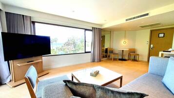 Una sala de estar moderna con un televisor de pantalla plana, un sofá, una mesa de centro y un comedor con sillas y una mesa.