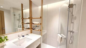 A modern bathroom with a large mirror, a white sink, and a glass shower enclosure.