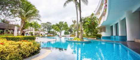 A swimming pool with tiled edges, surrounded by lush greenery and palm trees.