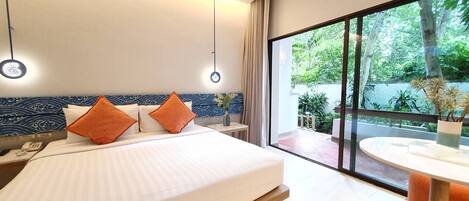 A modern hotel room with a large bed, a bedside table, a desk, and a view of the outdoors.