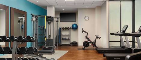 A gym with weightlifting equipment, treadmills, and exercise balls.
