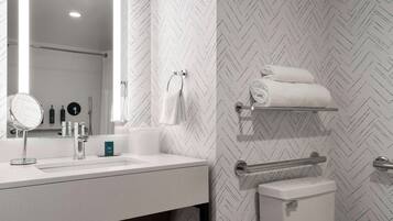 Un baño moderno con lavamanos blanco, espejo y toallero.