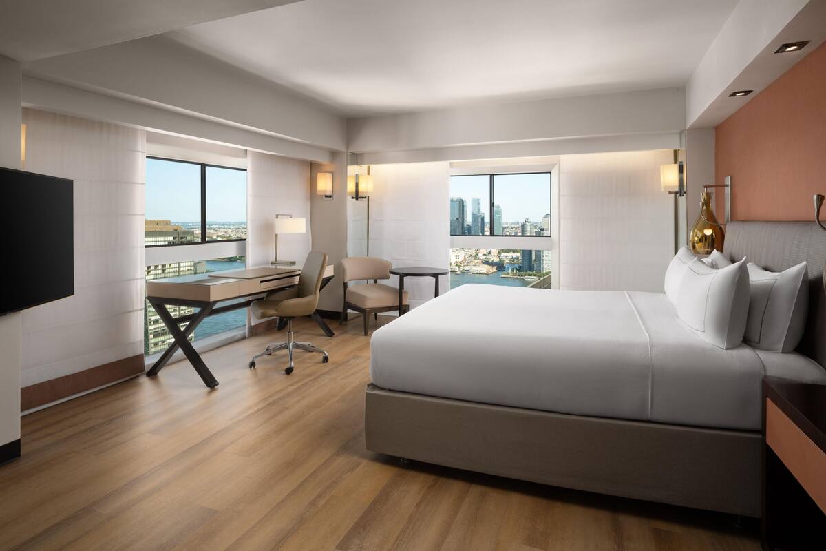 Une chambre d’hôtel moderne équipée d’un grand lit, d’un bureau, d’une chaise et d’une télévision.