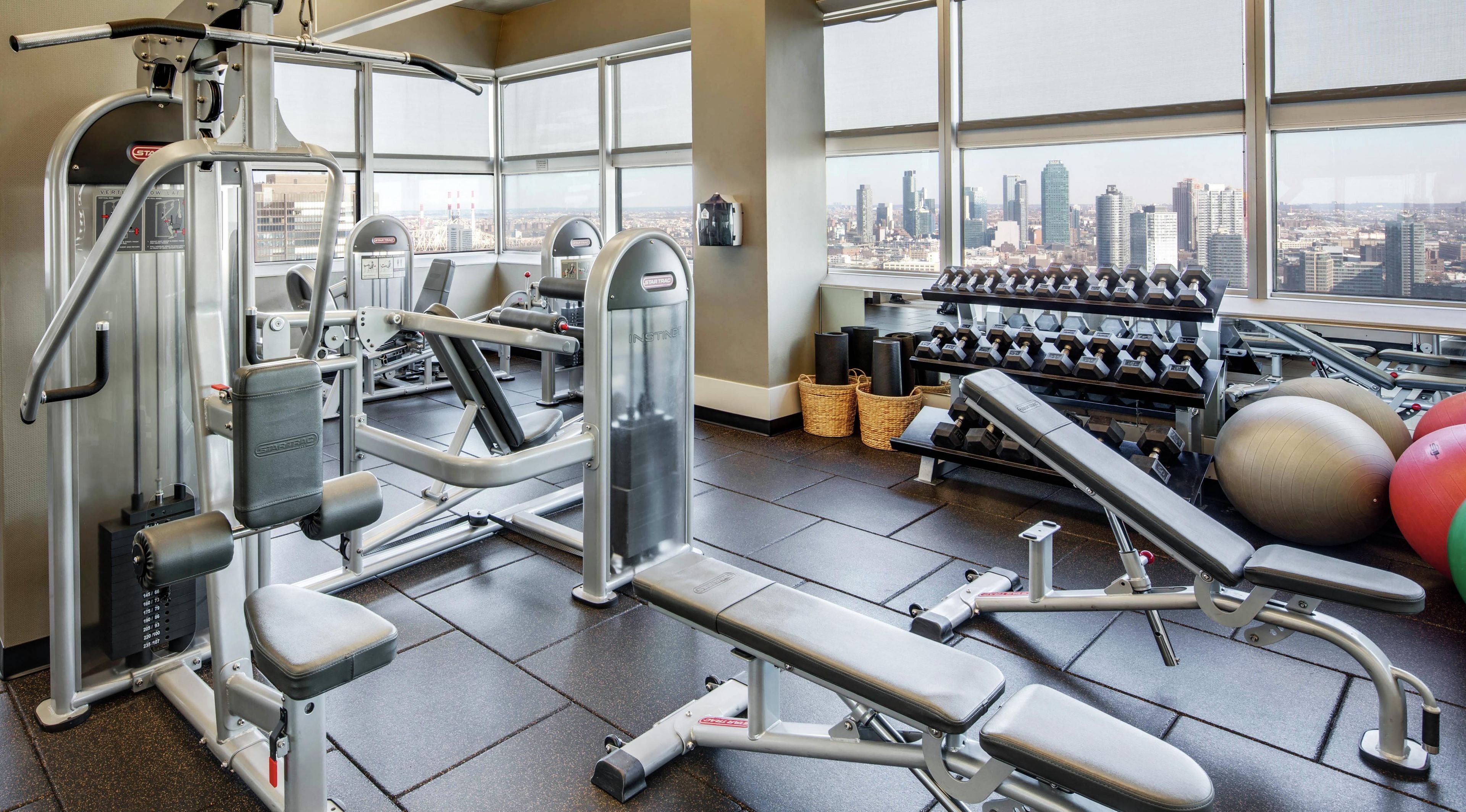 Een sportschool met diverse fitnessapparaten, waaronder krachttoestellen, gewichten en fitnessballen.