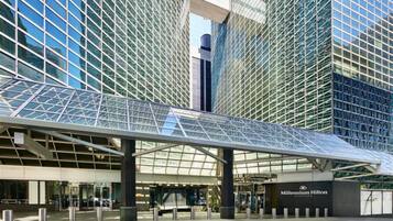 Una entrada de hotel moderna con un toldo de cristal y un llamativo letrero que dice 'Millennium Hilton'.