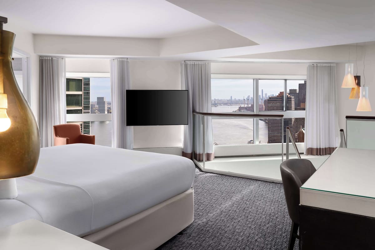 Une chambre d’hôtel avec un grand lit, un bureau, une chaise, une télévision et une vue sur la ville.