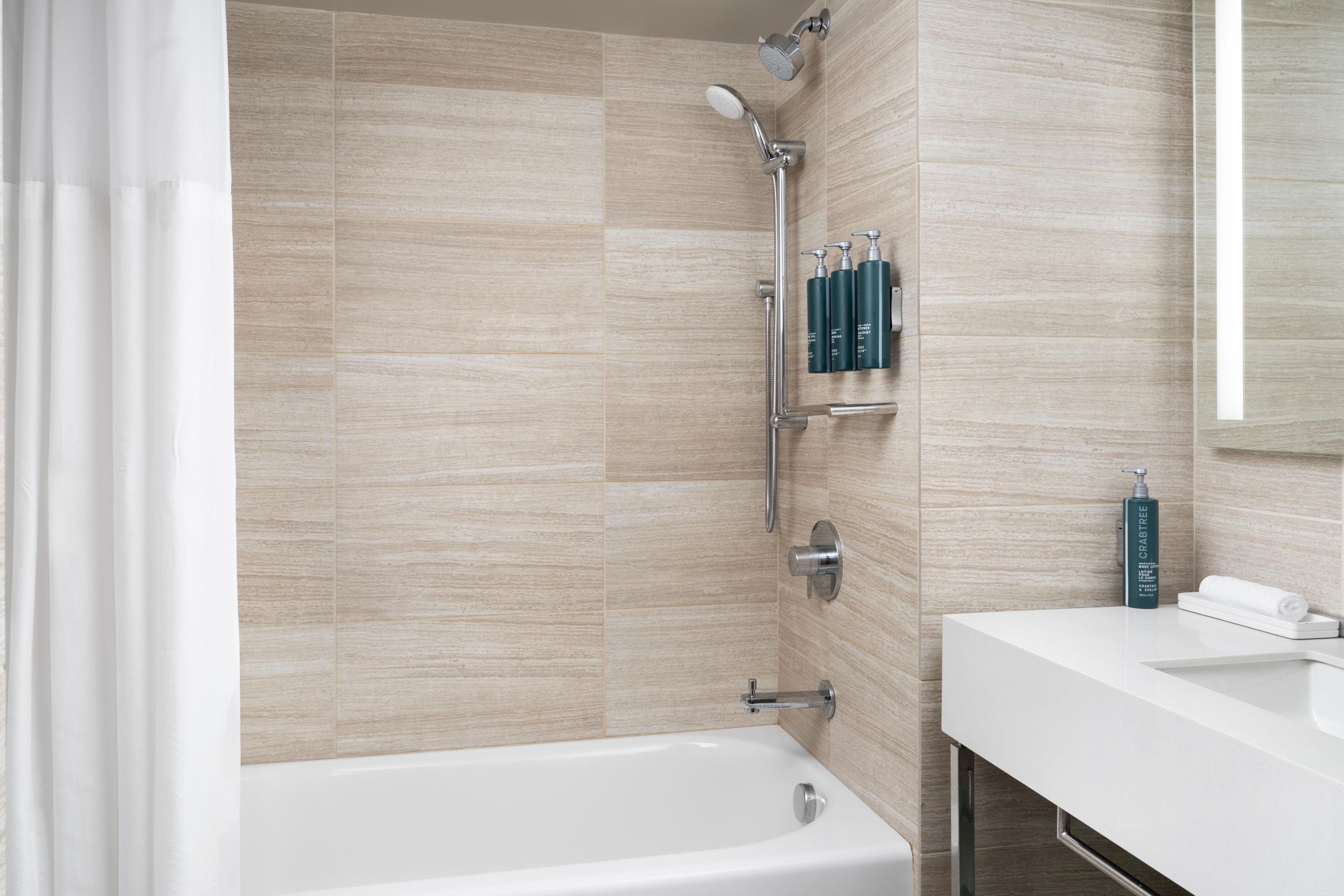 A modern bathroom with a bathtub, shower, and a vanity with toiletries.