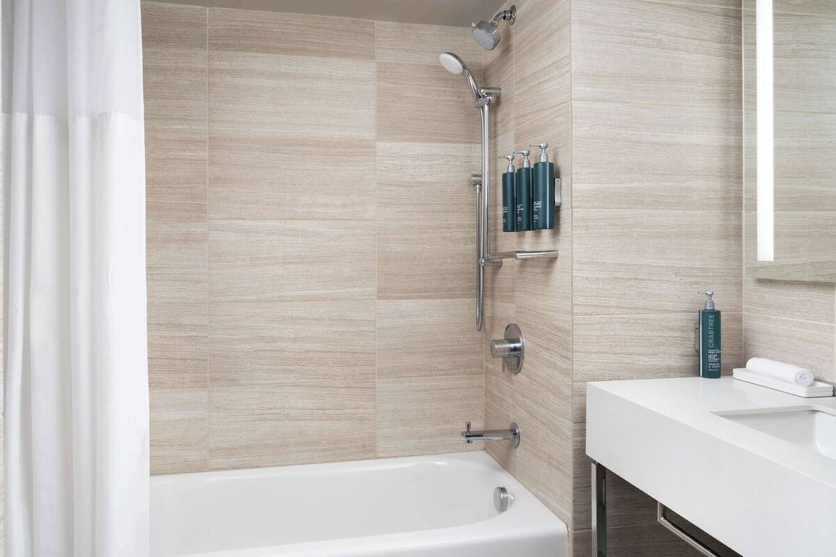 Une salle de bain moderne avec une baignoire, une douche et un lavabo blanc.