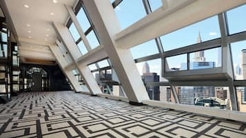 Un hall d’entrée spacieux, doté d’un sol orné de motifs géométriques, de grandes fenêtres offrant une vue sur la ville et d’une architecture moderne.
