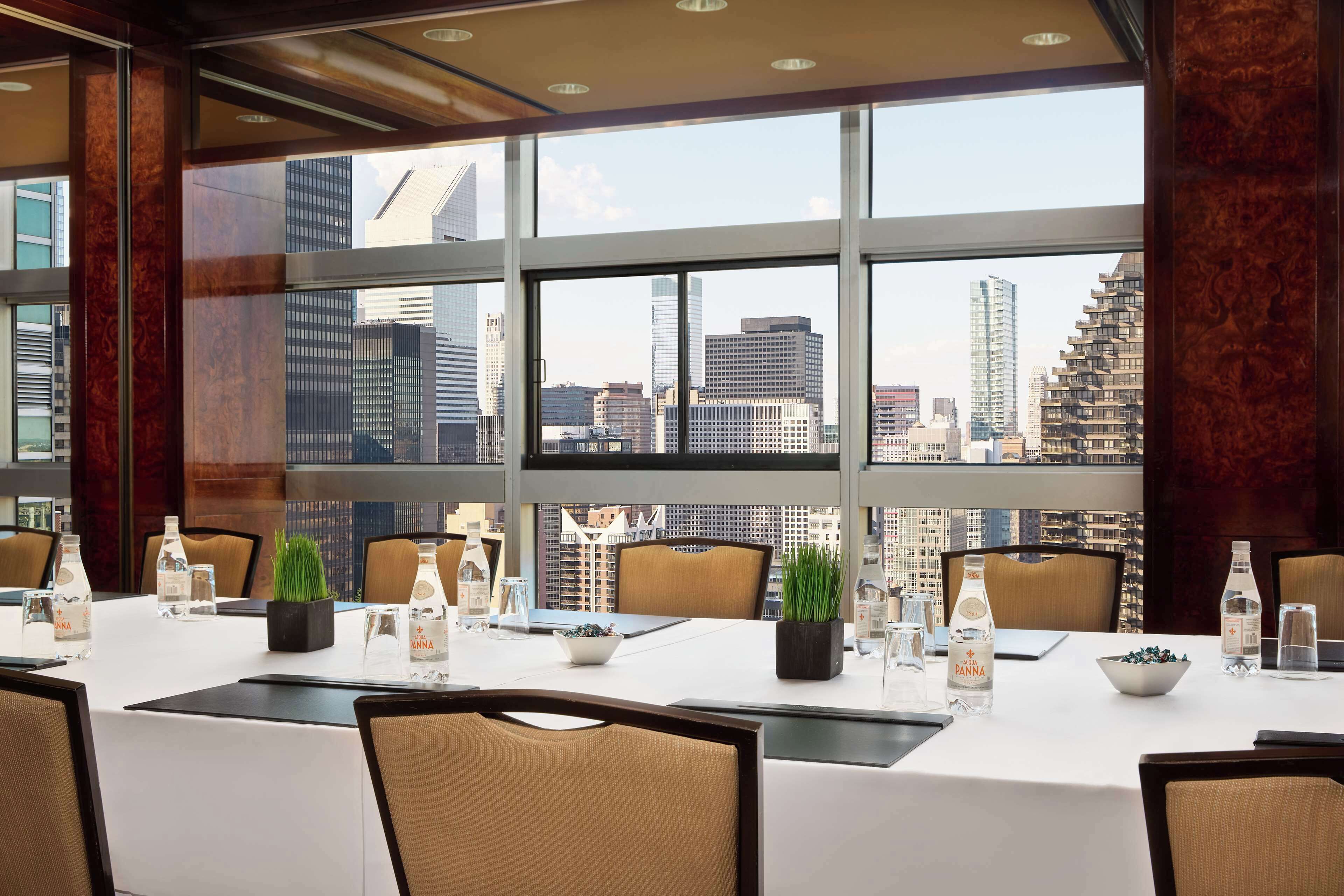 A conference room with a city view, large windows, and a table set for a meeting.