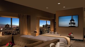 Een luxueuze slaapkamer met een groot bed, een bank en een televisie waarop de Empire State Building te zien is.
