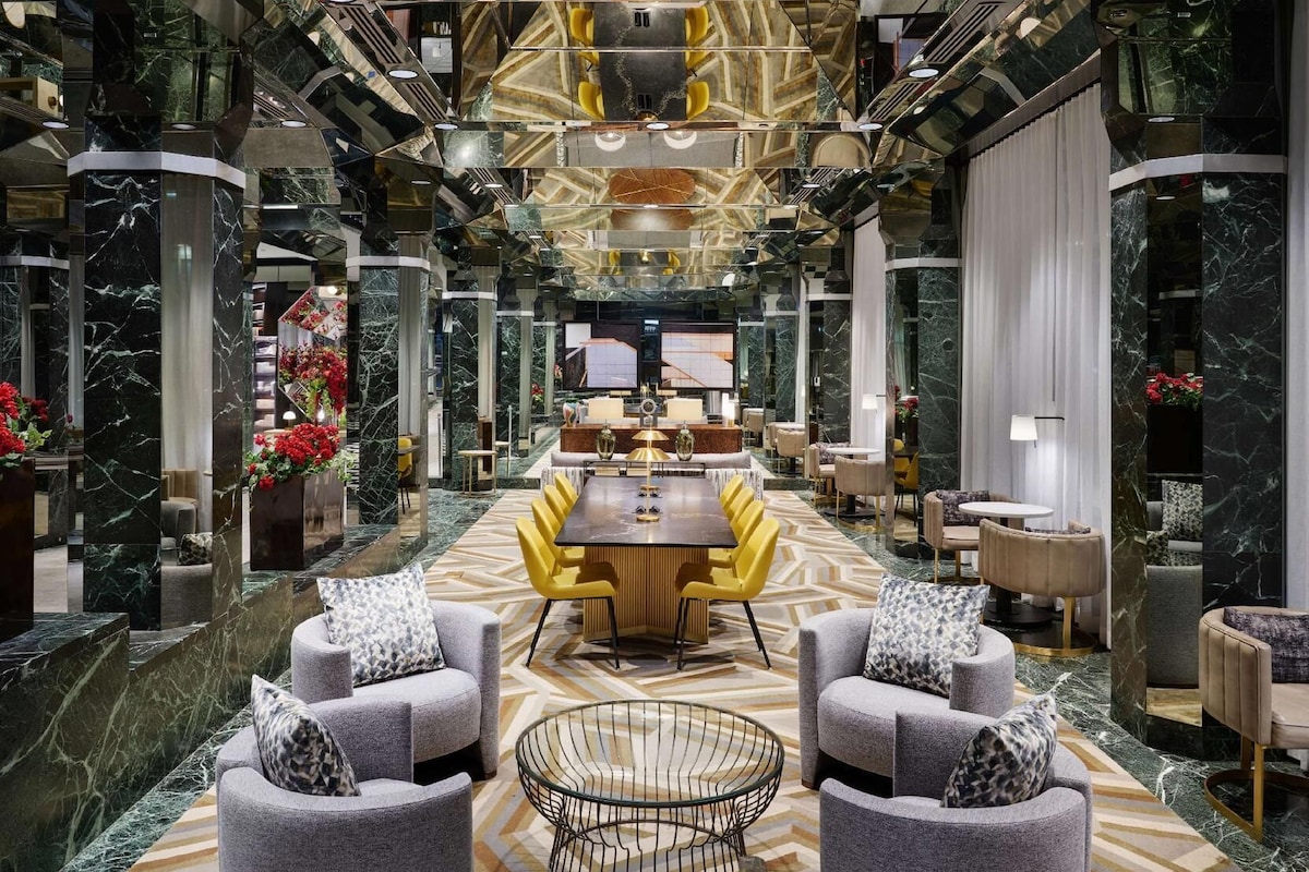 A spacious lobby with a central dining area, marble flooring, and modern furniture.