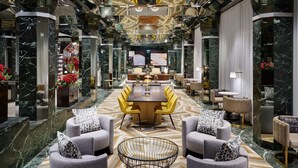 Een luxe lobby met een centraal gelegen eetgedeelte, marmeren vloeren en moderne meubels.