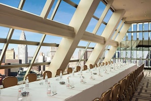 A conference room with a long table, chairs, and a city view through large windows.