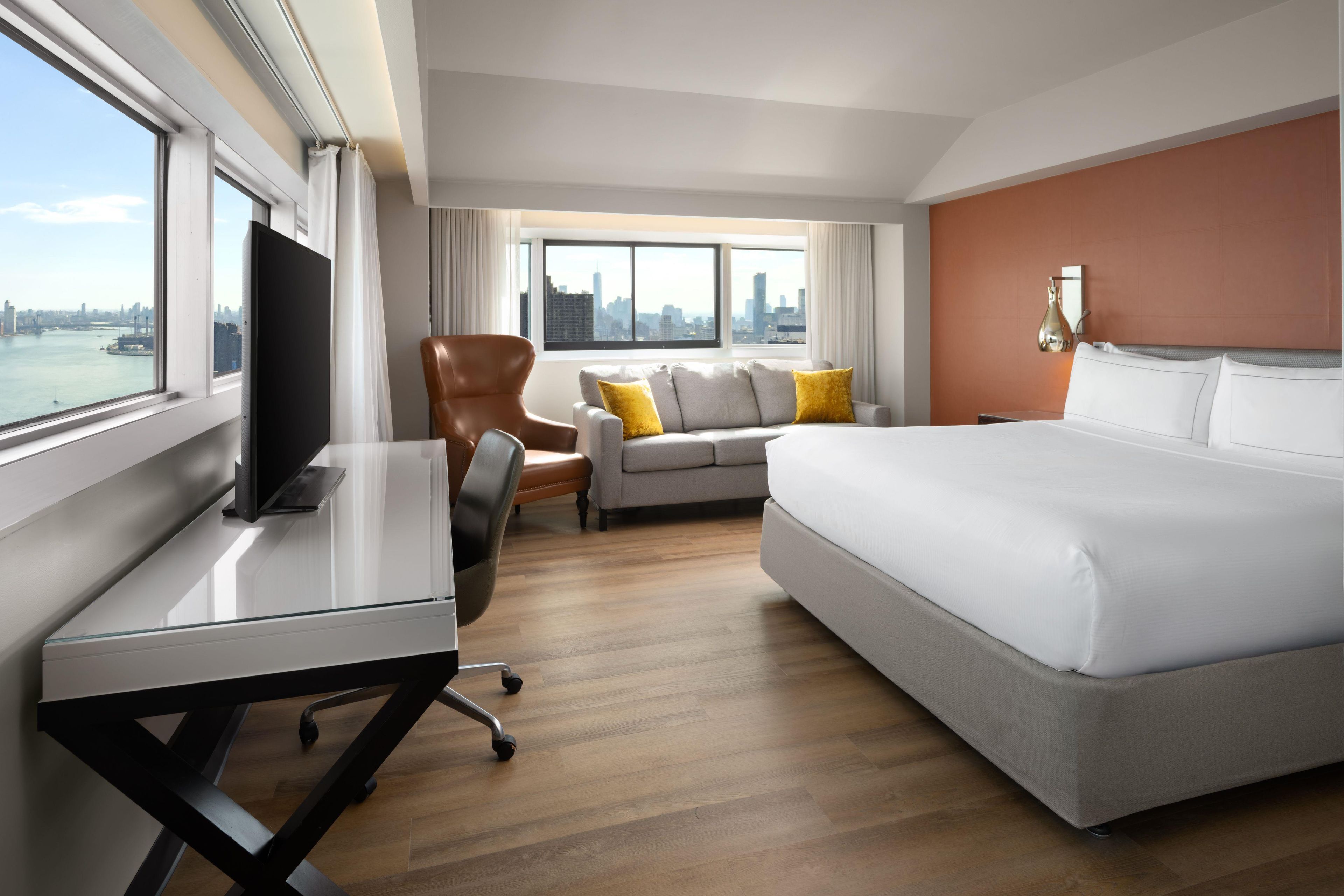 Une chambre d’hôtel équipée d’un lit, d’un bureau, d’une chaise, d’un canapé et d’une télévision.