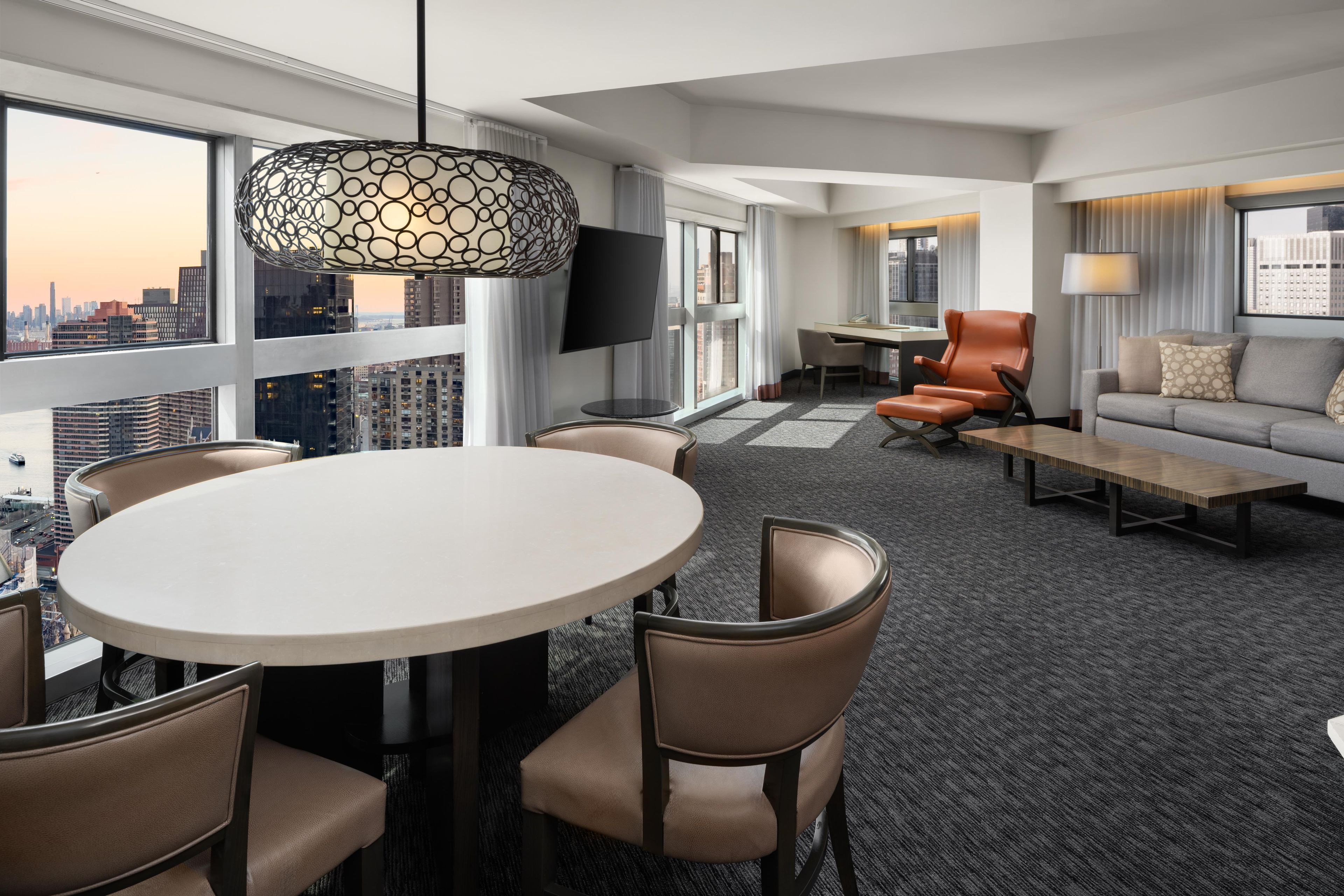 Een moderne hotelkamer met een eethoek, een bank en een televisie.