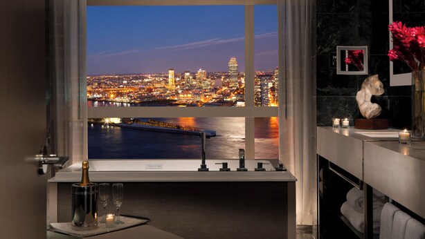Een moderne badkamer met een groot raam met uitzicht op een stadsbeeld bij nacht.