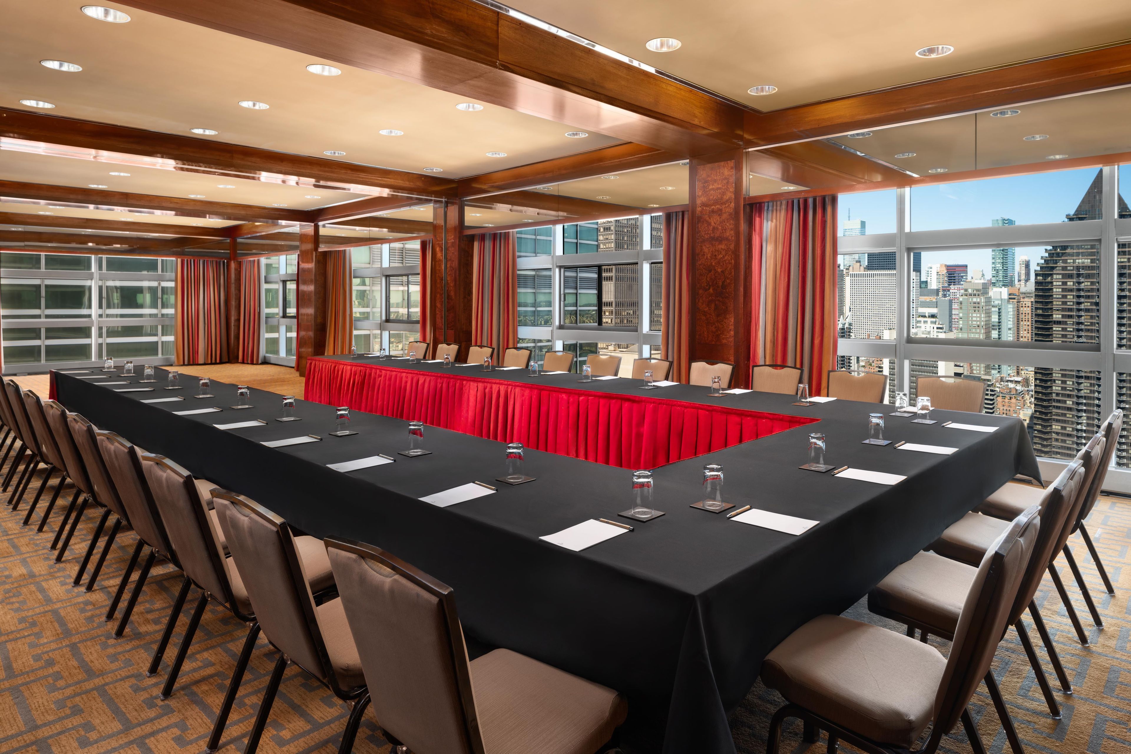 A conference room with a long table, chairs, and a city view.
