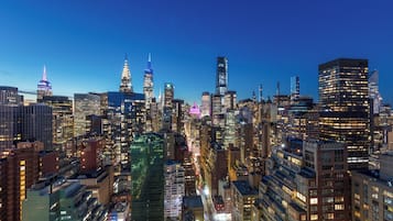 Eine beleuchtete Stadtlandschaft bei Nacht mit hoch aufragenden Wolkenkratzern und belebten Straßen.