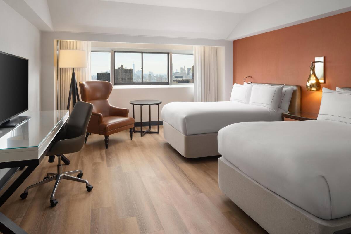 Une chambre d’hôtel comprenant un lit, un bureau, une chaise, une petite table et un téléviseur.