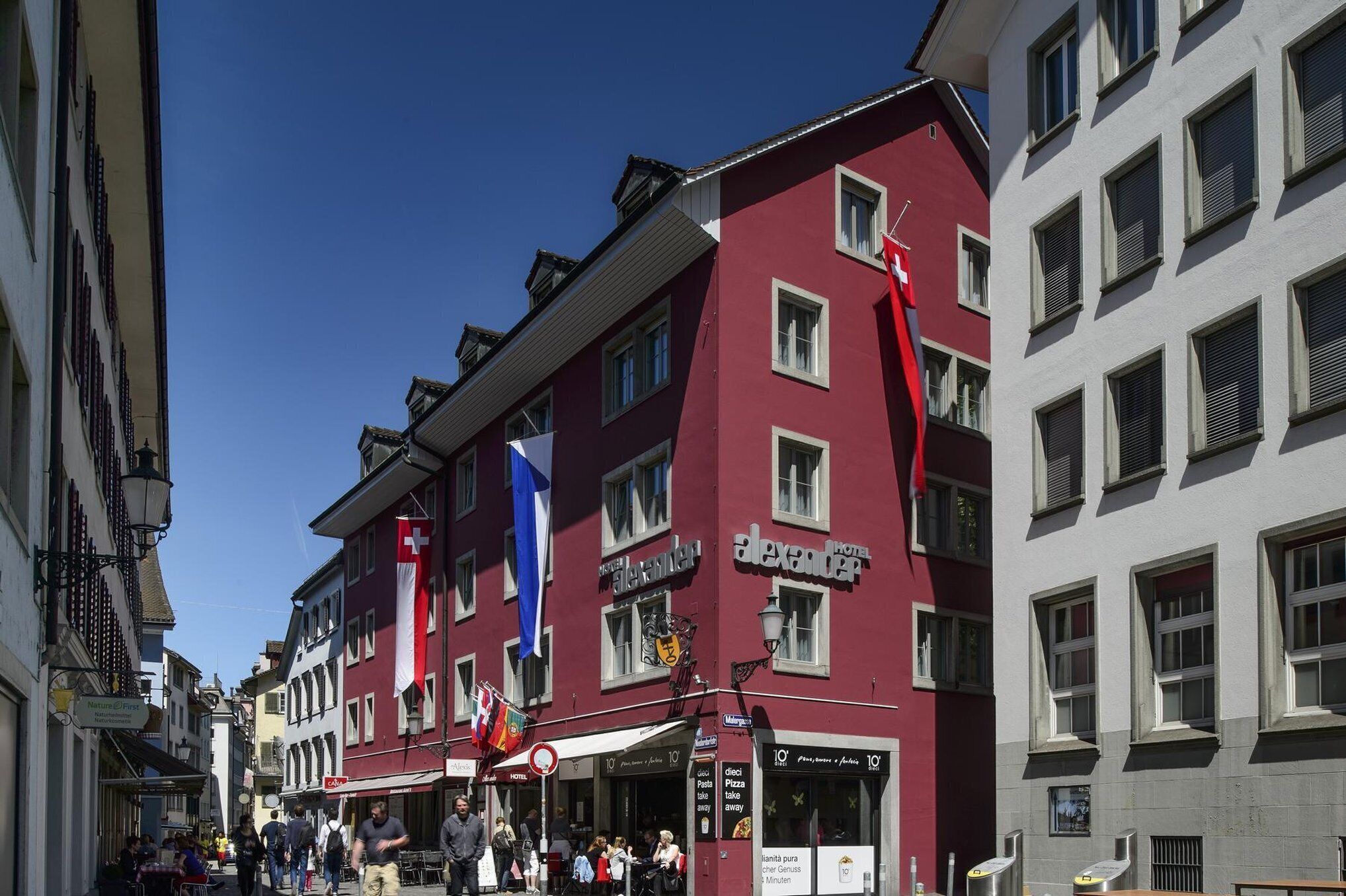 A red building with multiple windows and a sign for 'Hotel Alexander'.