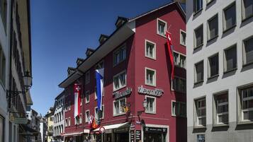 A red building with multiple windows and a sign for 'Hotel Alexander'.