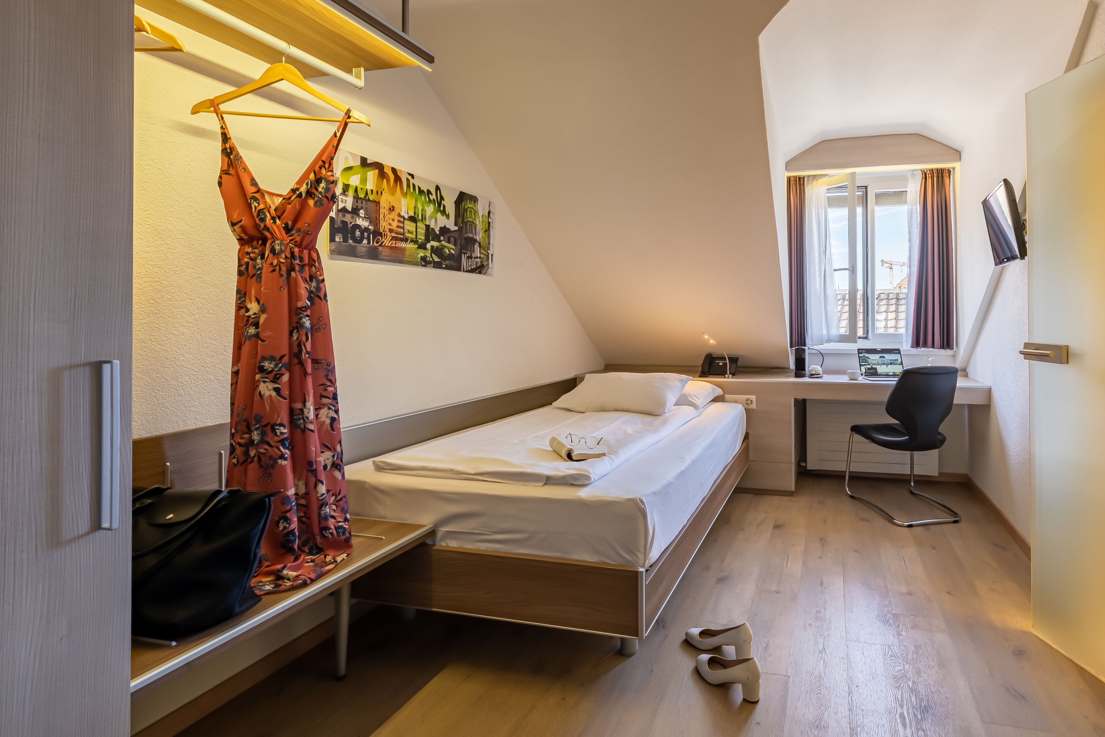 A compact room with a bed, a desk, and a chair.