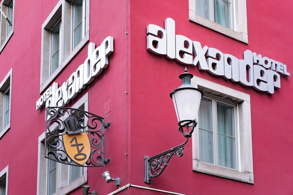 A red building with a sign reading "Hotel Alexander."