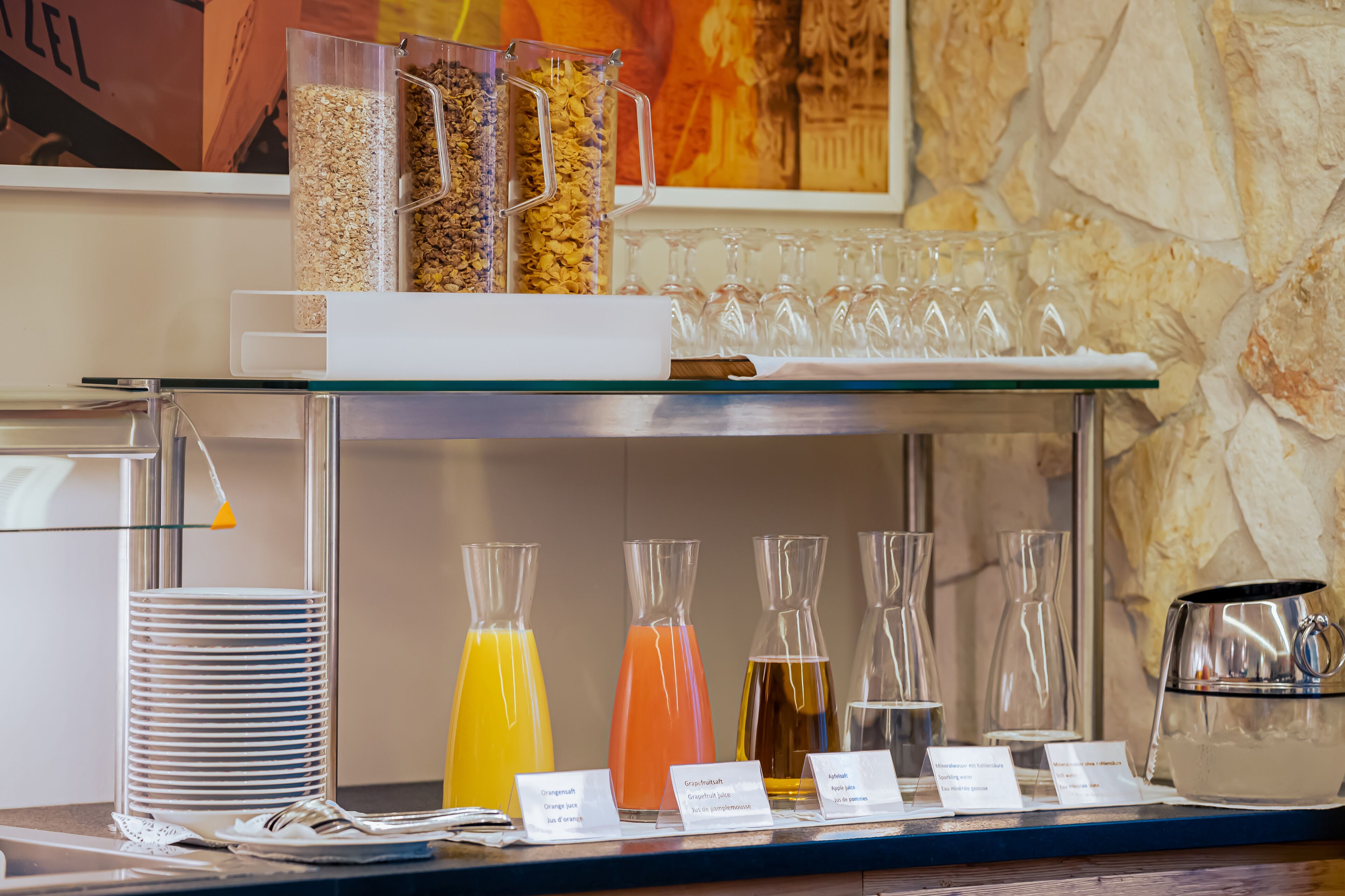 A breakfast bar with various food and drink options, including cereal, juices, and a coffee pot.